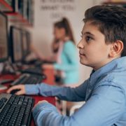 Młody chłopiec wykorzystuje komputer dla ucznia do nauki w sali szkolnej.
