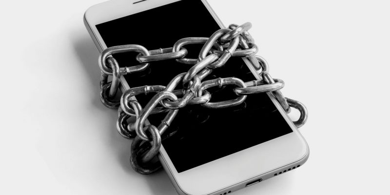 Łańcuch owinięty wokół smartfona – bezpieczne telefony blokują dostęp do wrażliwych danych niczym łańcuch.