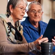 Starsze małżeństwo przed tabletem próbuje sobie poradzić jako seniorzy w Internecie.