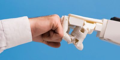 Czy sztuczna inteligencja zabierze nam pracę? Na zdjęciu człowiek zbija żółwia z robotem.
