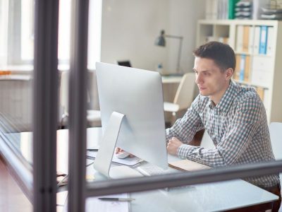 Zasady bezpiecznej pracy przy komputerze. Na zdjęciu mężczyzna pracuje przy komputerze.