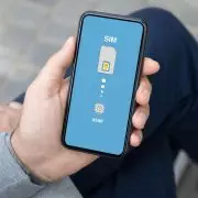 Mężczyzna trzyma w dłoni smartfon, na którego ekranie widać ustawienia SIM i eSIM na niebieskim tle.